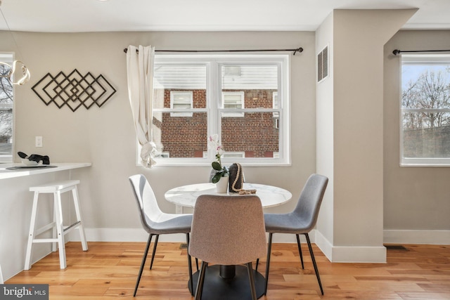 dining room featuring visible vents, baseboards, and wood finished floors