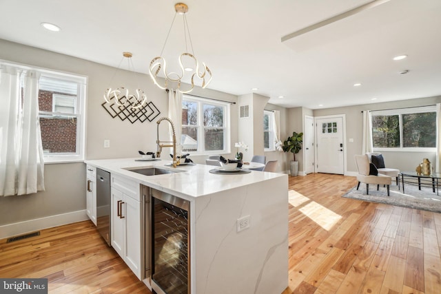 kitchen featuring visible vents, a sink, wine cooler, light wood-style floors, and stainless steel dishwasher