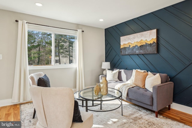 living area featuring recessed lighting, wood walls, baseboards, and wood finished floors