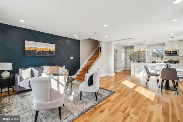 living room with light wood-style flooring, recessed lighting, stairway, baseboards, and an accent wall