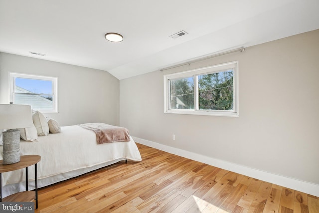 bedroom featuring visible vents, lofted ceiling, baseboards, and wood finished floors