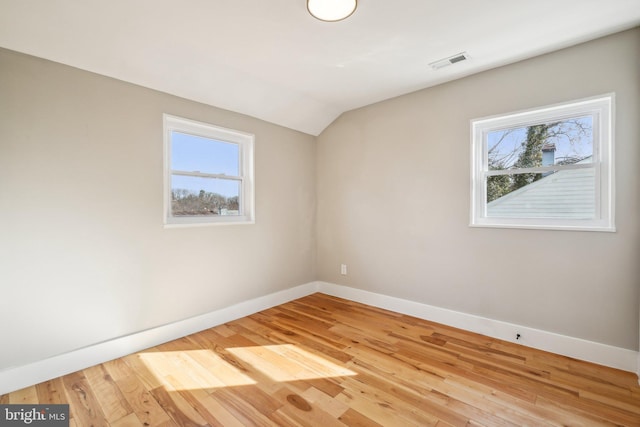 spare room featuring wood finished floors, a healthy amount of sunlight, visible vents, and baseboards