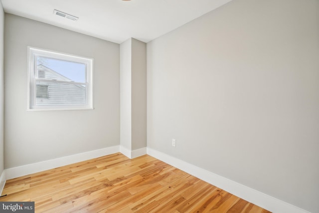 unfurnished room featuring visible vents, baseboards, and wood finished floors