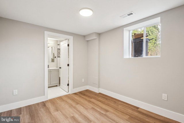 unfurnished room featuring light wood-style floors, visible vents, and baseboards