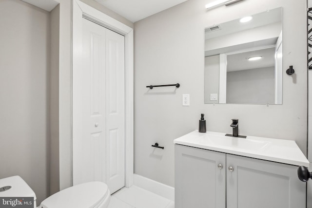 bathroom featuring vanity, toilet, visible vents, and a closet