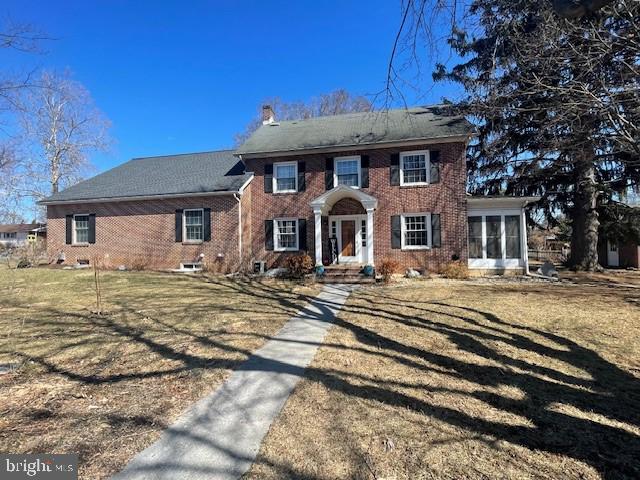 colonial home with a chimney and brick siding