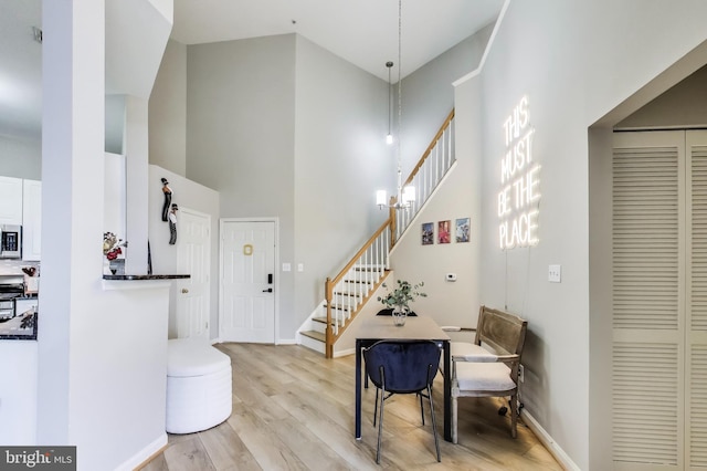 entrance foyer featuring baseboards, light wood-style flooring, a high ceiling, and stairs