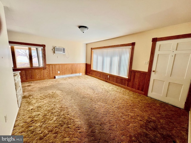 unfurnished room with a baseboard heating unit, wainscoting, a wall unit AC, carpet flooring, and wooden walls