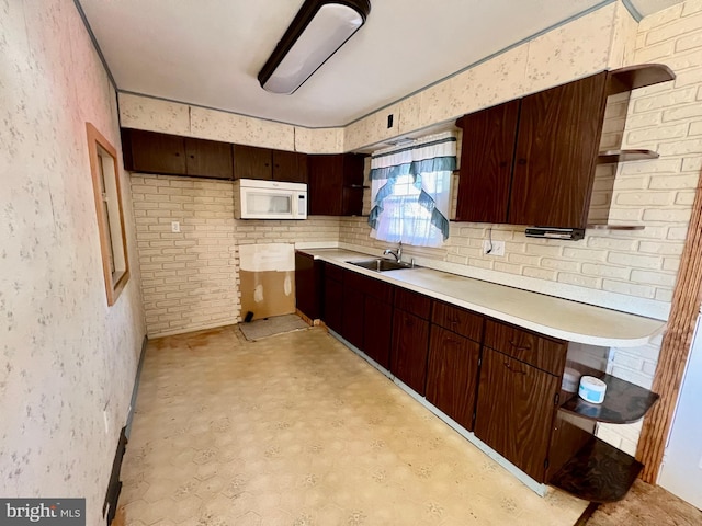 kitchen with white microwave, a sink, open shelves, and light countertops
