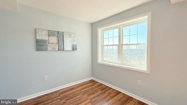 spare room featuring dark wood-style flooring and baseboards