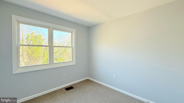 carpeted spare room with visible vents and baseboards