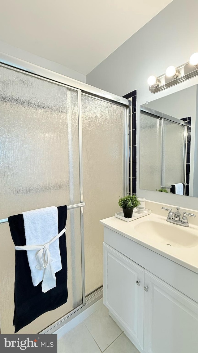 bathroom with tile patterned flooring, a shower with shower door, and vanity