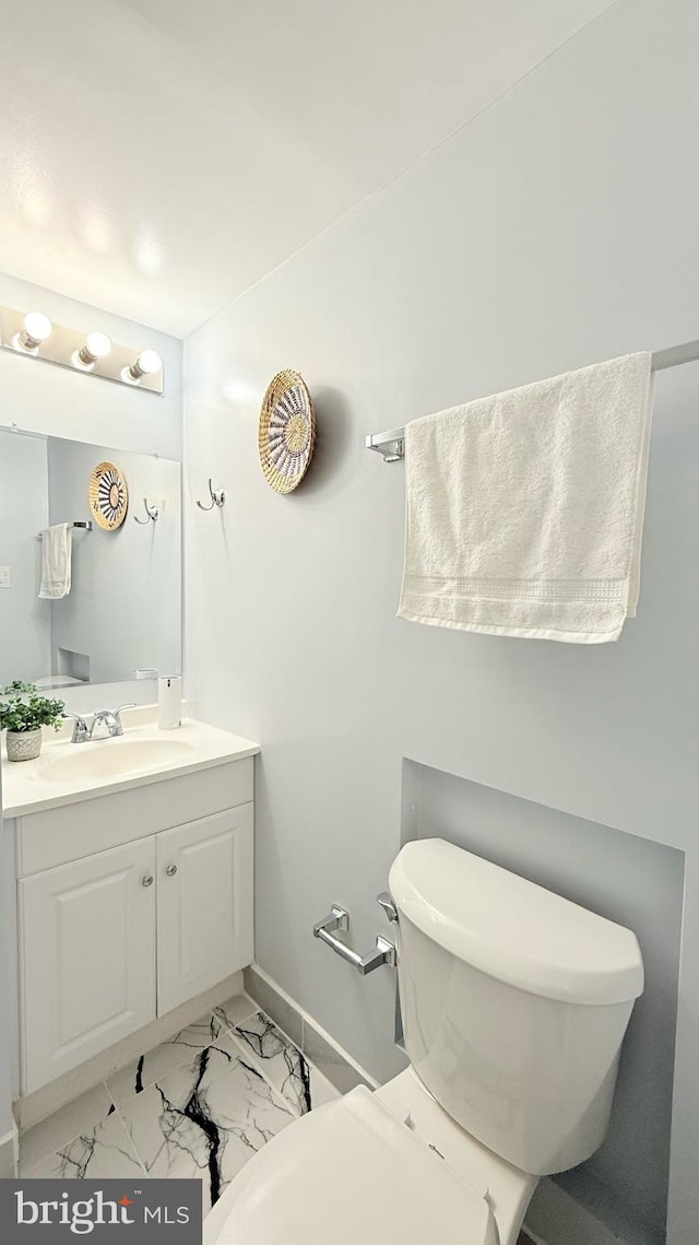 bathroom featuring marble finish floor, baseboards, vanity, and toilet