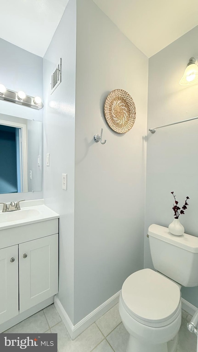 half bathroom with tile patterned flooring, toilet, vanity, visible vents, and baseboards