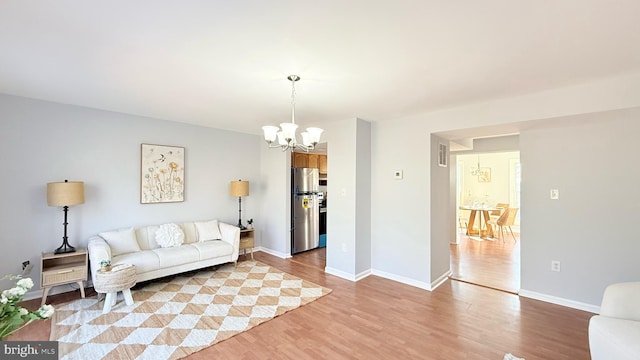 living room featuring baseboards, light wood-style floors, and an inviting chandelier