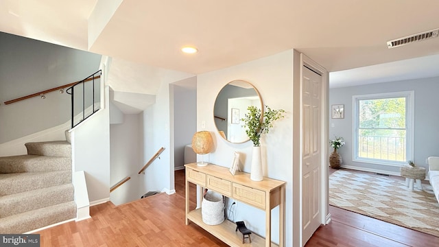 corridor featuring visible vents, baseboards, and wood finished floors