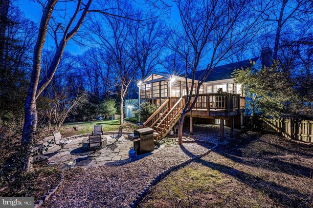 view of play area with fence, an outdoor fire pit, stairs, a deck, and a patio area