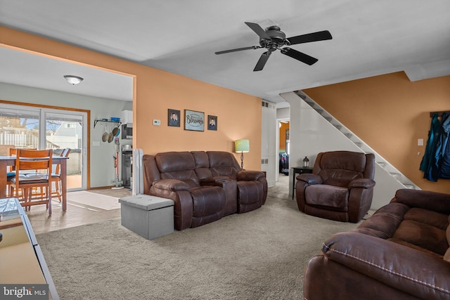 carpeted living room with stairway and ceiling fan