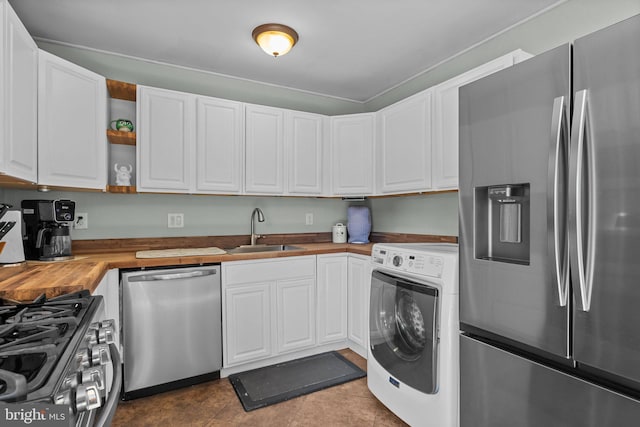 kitchen with washer / dryer, a sink, appliances with stainless steel finishes, wood counters, and white cabinetry