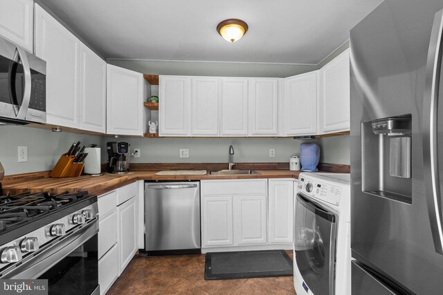 kitchen featuring washer / dryer, a sink, appliances with stainless steel finishes, wood counters, and white cabinetry