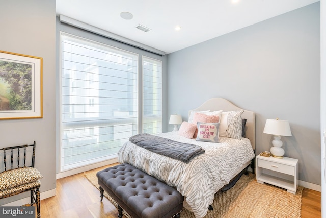 bedroom with wood finished floors, visible vents, and baseboards