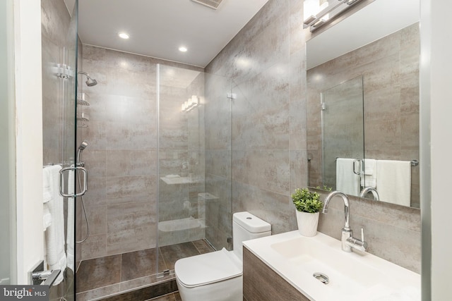 bathroom with toilet, a shower stall, and tile walls