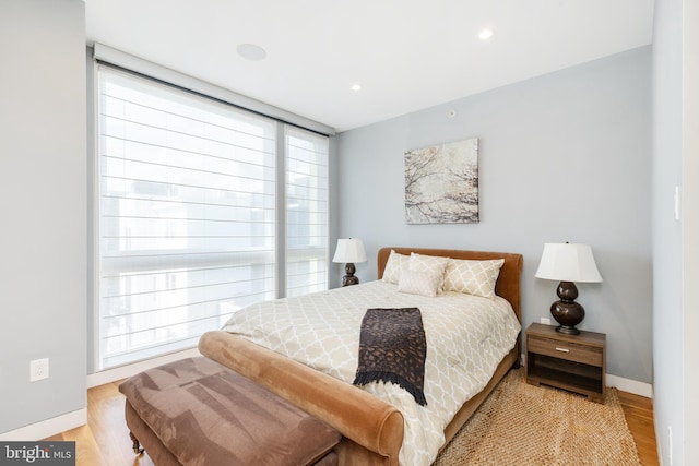 bedroom featuring baseboards, wood finished floors, and recessed lighting