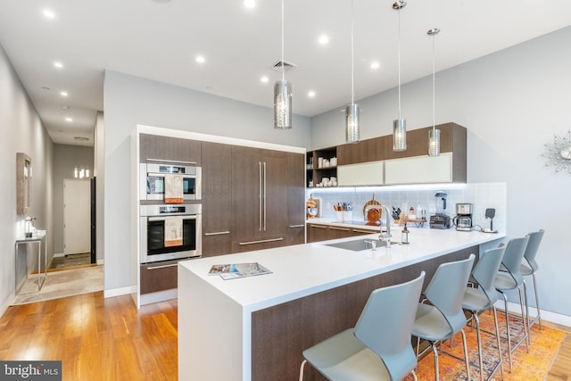 kitchen with open shelves, tasteful backsplash, modern cabinets, a peninsula, and a kitchen bar