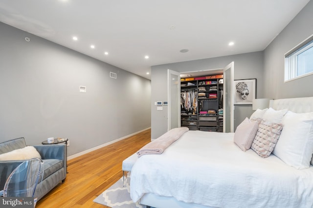 bedroom featuring recessed lighting, visible vents, light wood-style flooring, a spacious closet, and baseboards