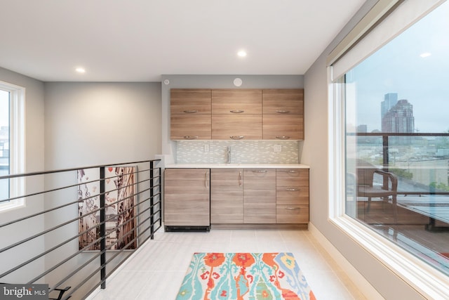 interior space with light tile patterned floors, backsplash, light countertops, a city view, and a sink