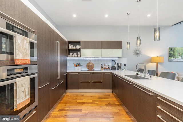 kitchen with dark brown cabinetry, modern cabinets, light countertops, and a sink