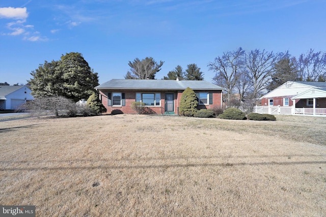 view of front facade featuring fence, a front lawn, and brick siding