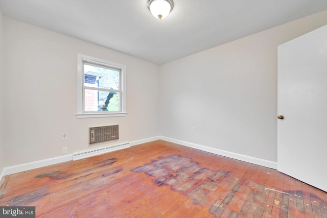 empty room with hardwood / wood-style flooring, baseboards, and a baseboard heating unit