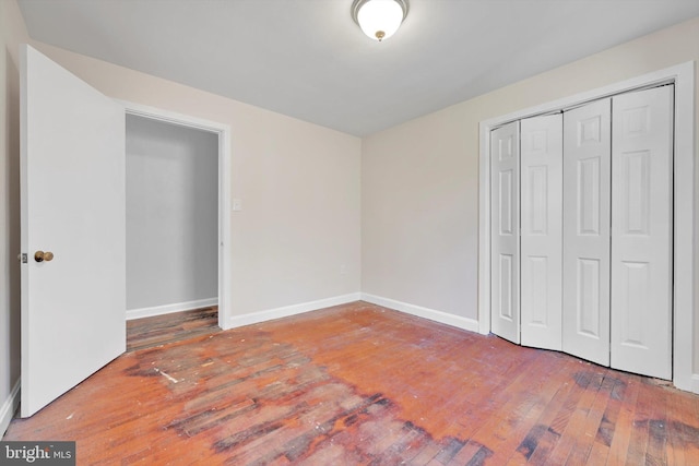 unfurnished bedroom featuring a closet, baseboards, and hardwood / wood-style flooring