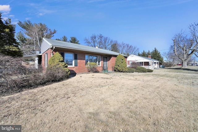 ranch-style home featuring a front yard and brick siding