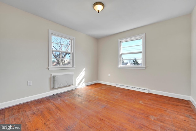 unfurnished room featuring baseboards, hardwood / wood-style floors, visible vents, and a healthy amount of sunlight