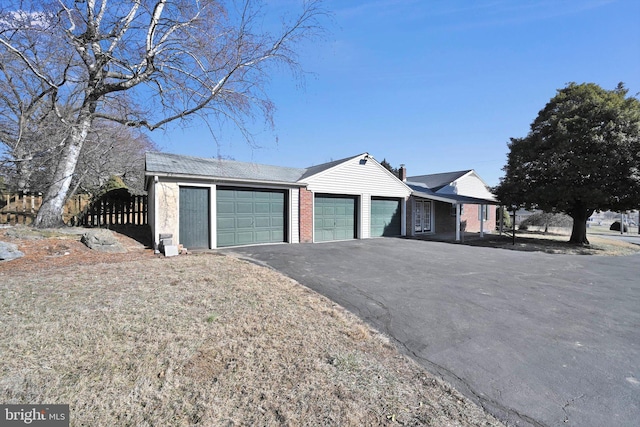 view of front facade with brick siding, a chimney, fence, a garage, and driveway