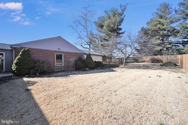 view of side of home featuring brick siding and fence