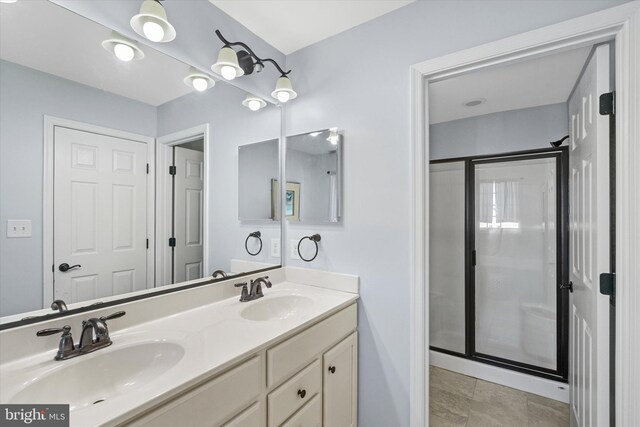 bathroom featuring a shower stall, double vanity, and a sink