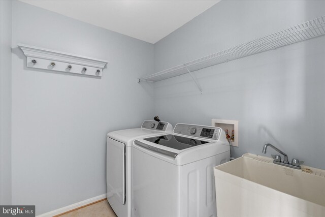 clothes washing area with a sink, washer and clothes dryer, baseboards, and laundry area