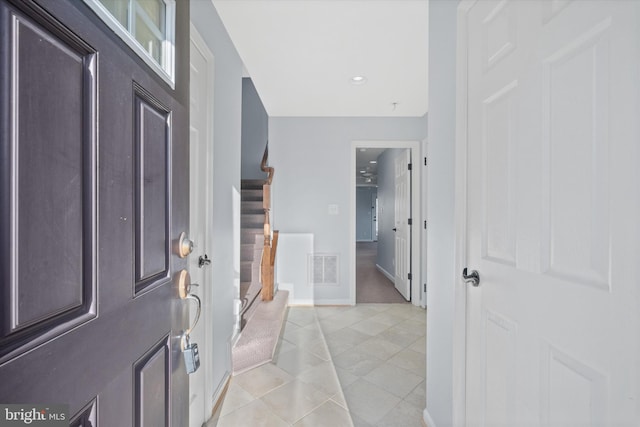 foyer entrance featuring baseboards, visible vents, stairway, and light tile patterned floors