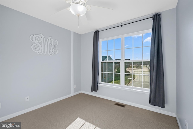 carpeted empty room with baseboards, visible vents, and ceiling fan