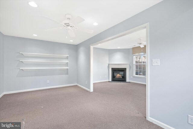 unfurnished living room featuring carpet flooring, a fireplace with flush hearth, baseboards, ceiling fan, and recessed lighting