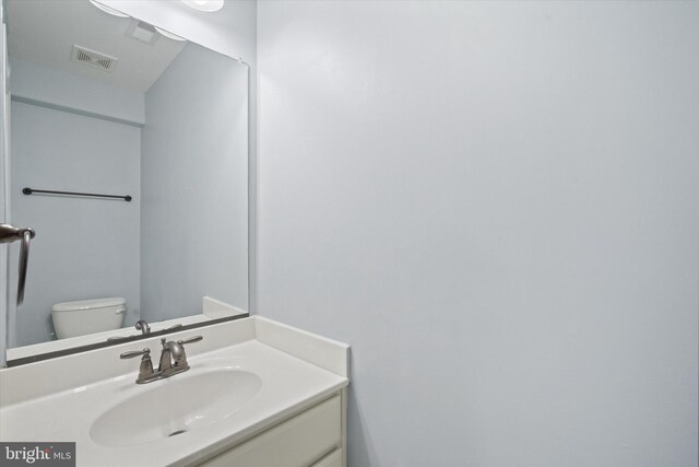 half bath featuring visible vents, toilet, and vanity