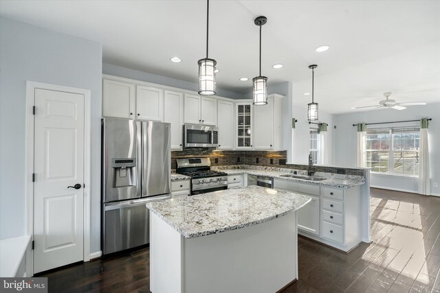 kitchen with white cabinetry, tasteful backsplash, stainless steel appliances, a sink, and a peninsula