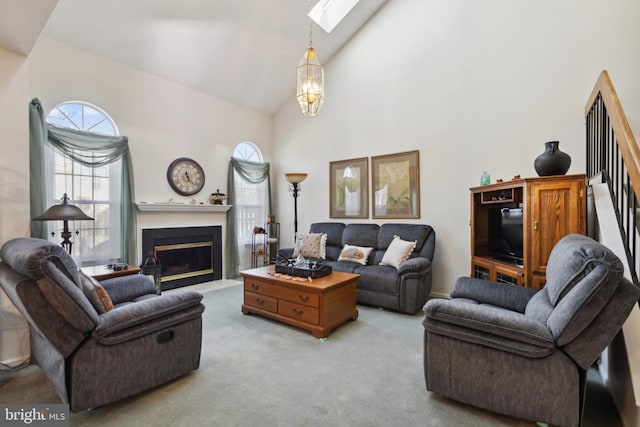 living area with a skylight, carpet, high vaulted ceiling, a fireplace with flush hearth, and a chandelier