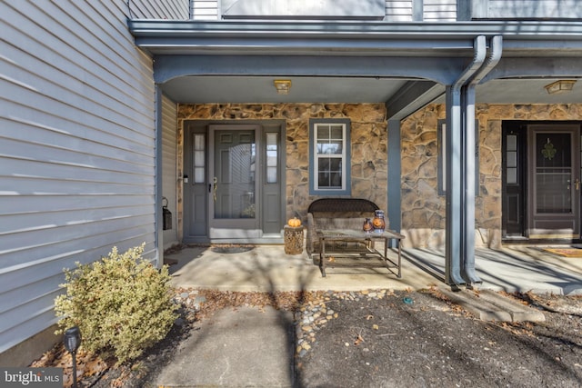 property entrance featuring stone siding and covered porch