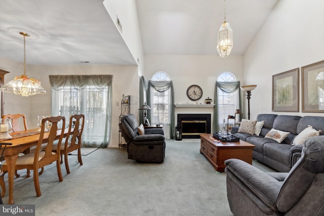 living area featuring high vaulted ceiling, a chandelier, light carpet, and a fireplace