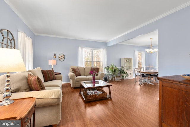 living area featuring baseboards, a notable chandelier, wood finished floors, and ornamental molding