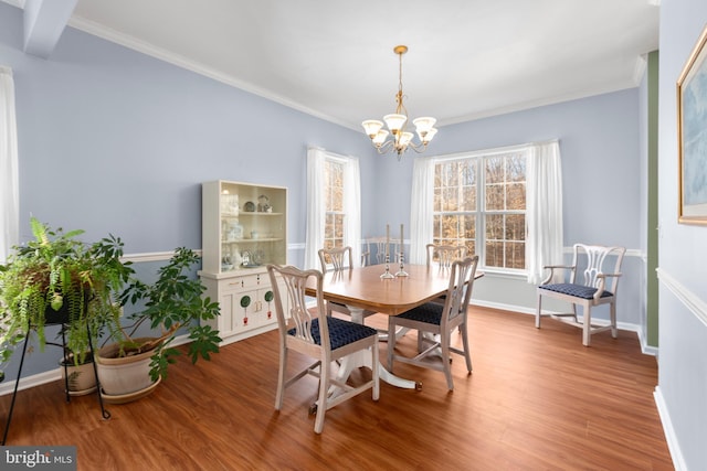 dining room with an inviting chandelier, wood finished floors, baseboards, and ornamental molding